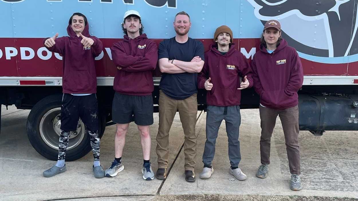 A group of men are standing in front of a moving truck.