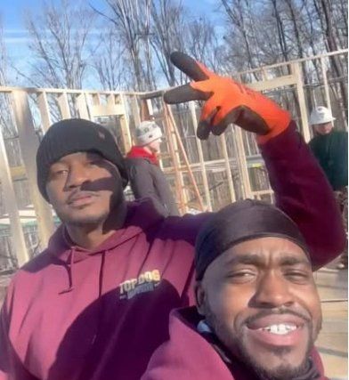 Two men posing for a picture with one wearing a top dog sweatshirt