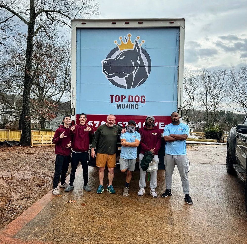 A group of men are standing in front of a top dog moving truck.