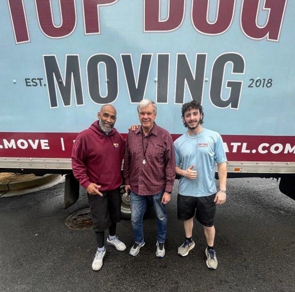 Three men standing in front of a top dog moving truck