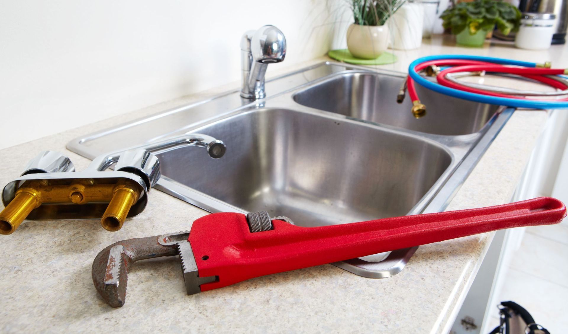 A red wrench is sitting on a kitchen counter next to a sink.