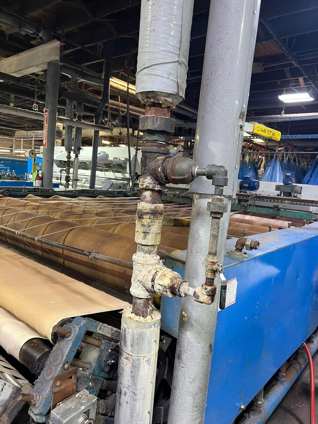 A machine in a factory with a lot of pipes coming out of it.