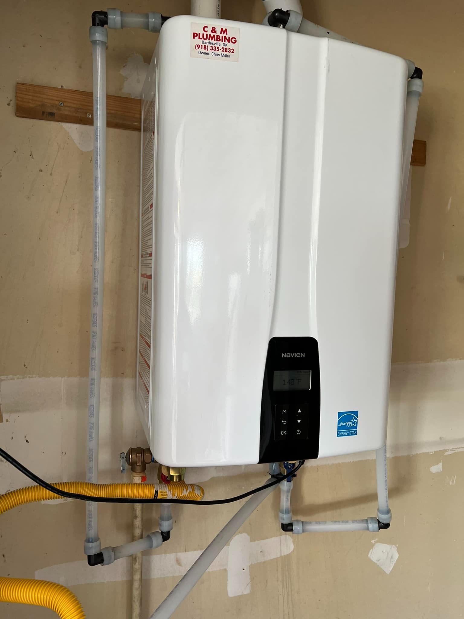 A white water heater is hanging on a wall.