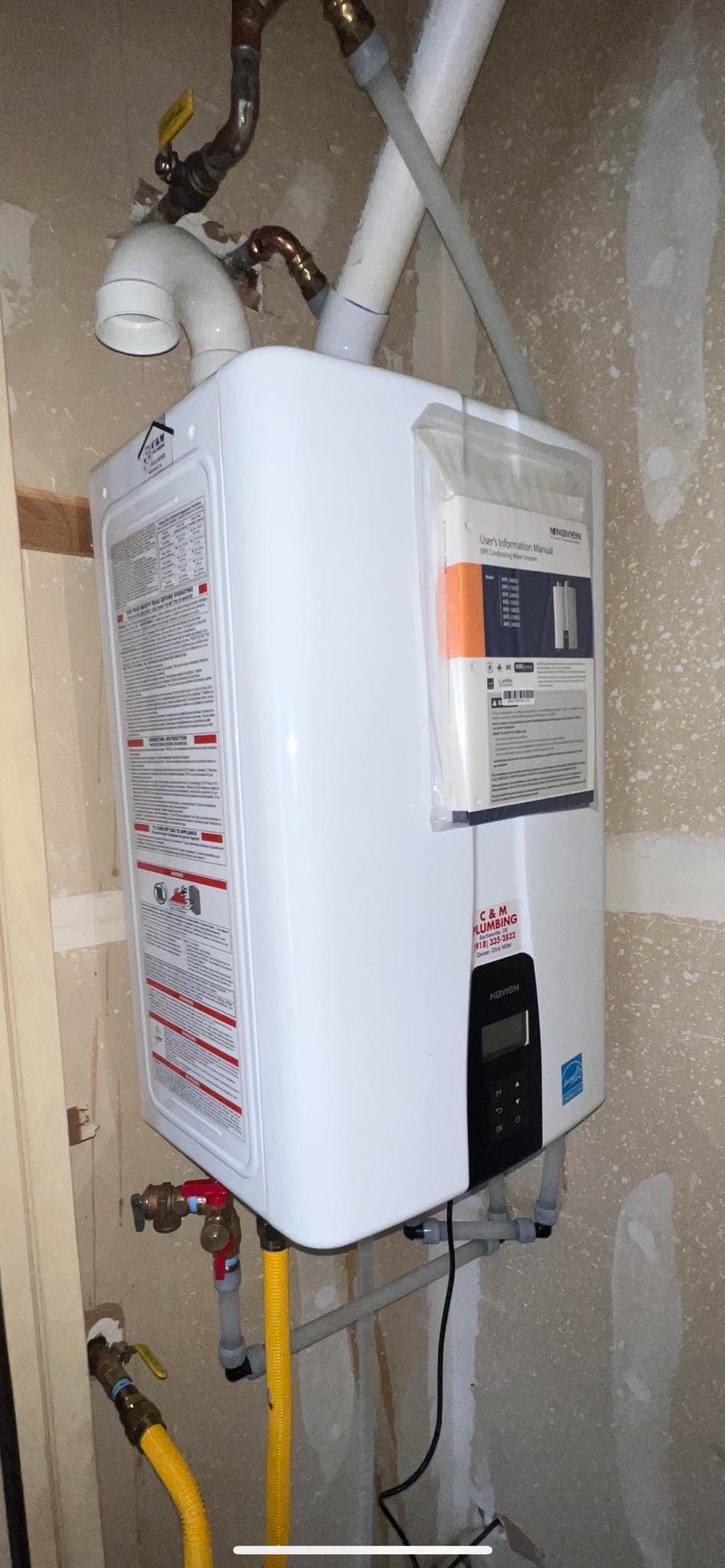 A white water heater is hanging on a wall next to a gas pipe.