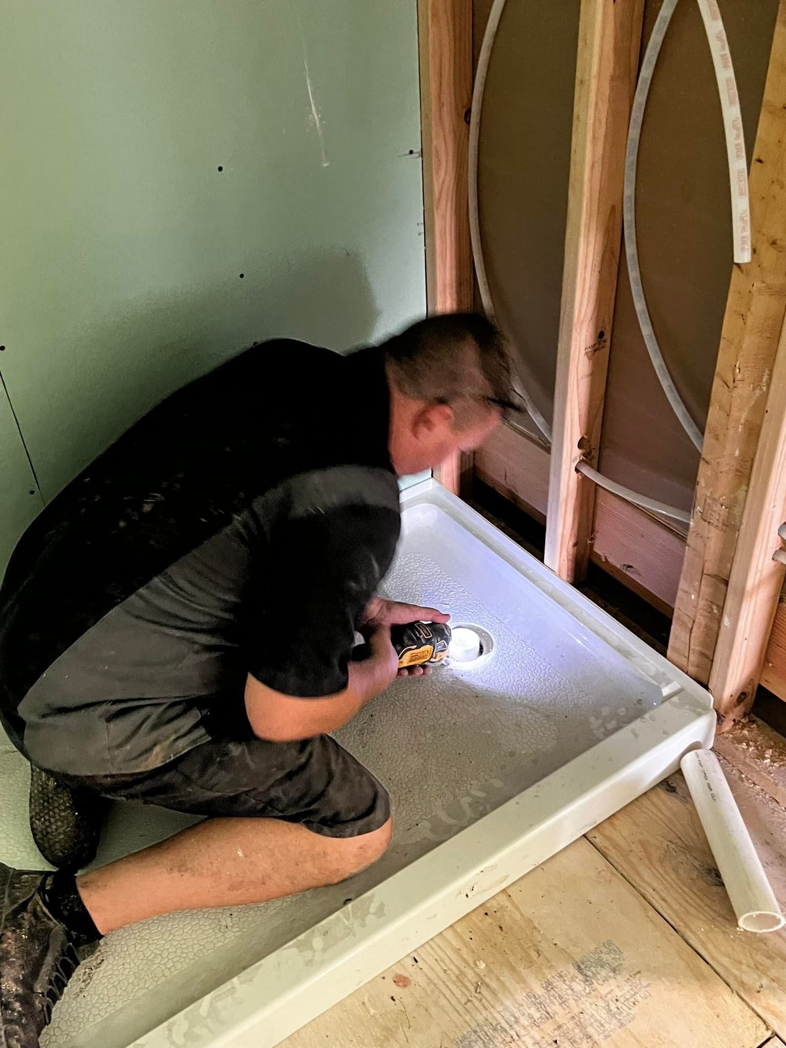A man is kneeling down in a room holding a drill.