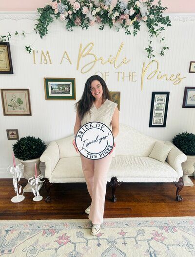 A woman is holding a sign that says i 'm a bride of the pines