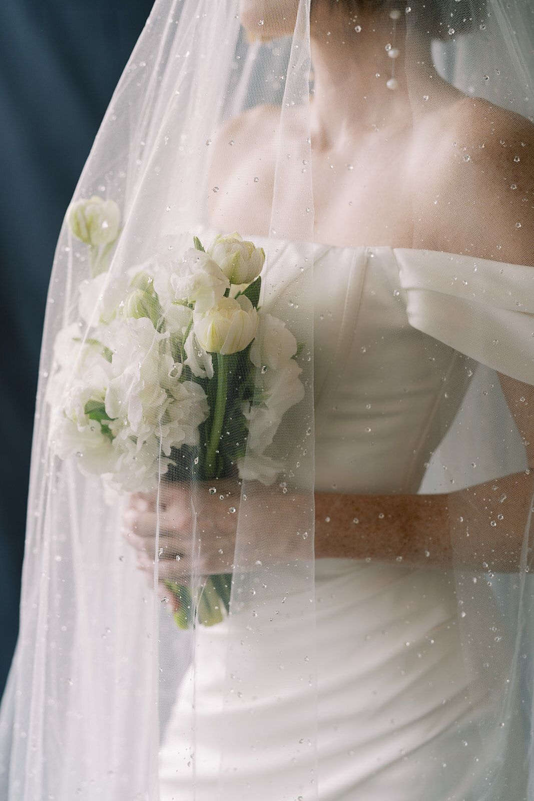 The bride is wearing a veil and holding a bouquet of white flowers.