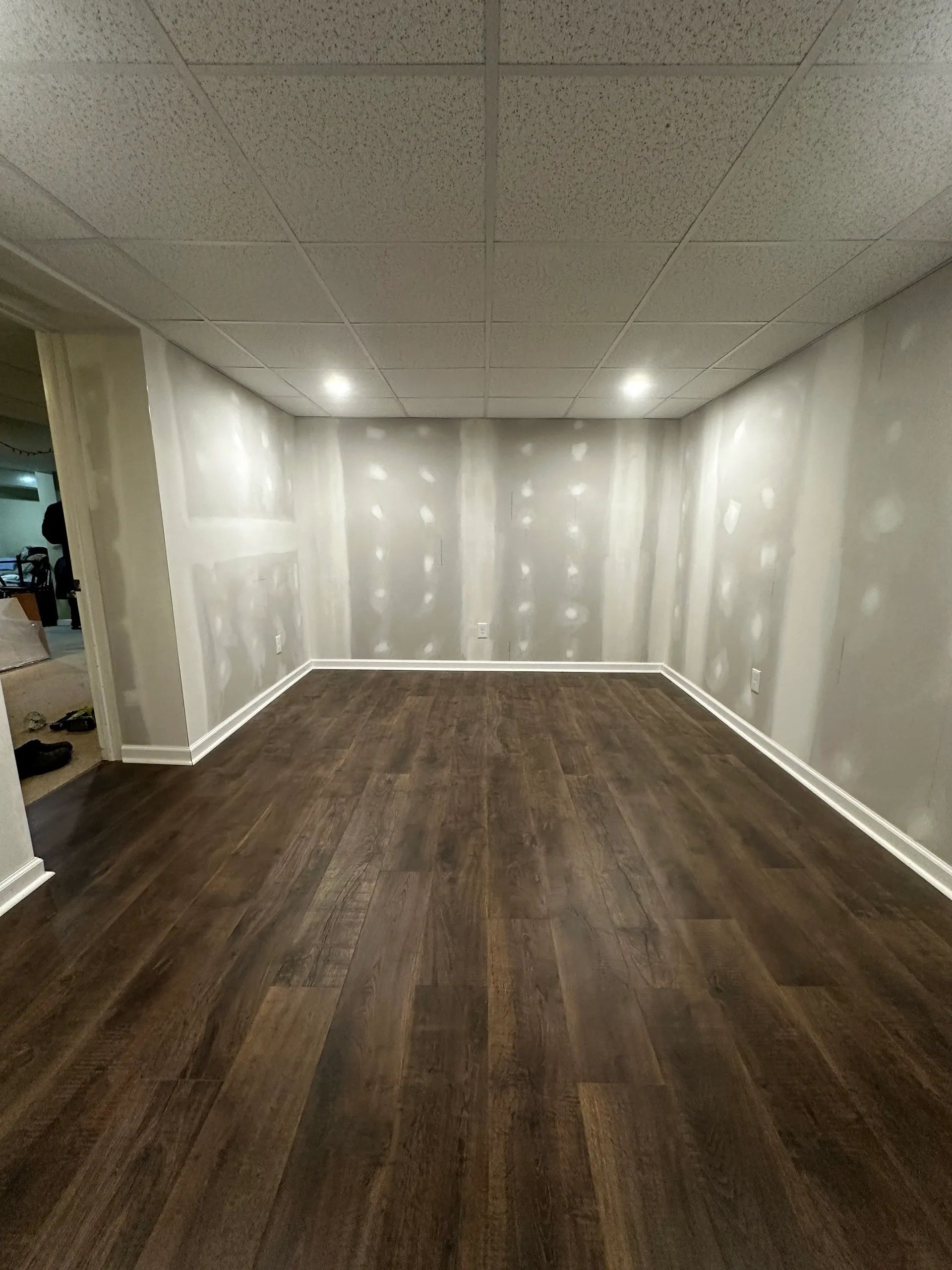 Empty room with dark wood floors, white walls, and recessed ceiling lights.