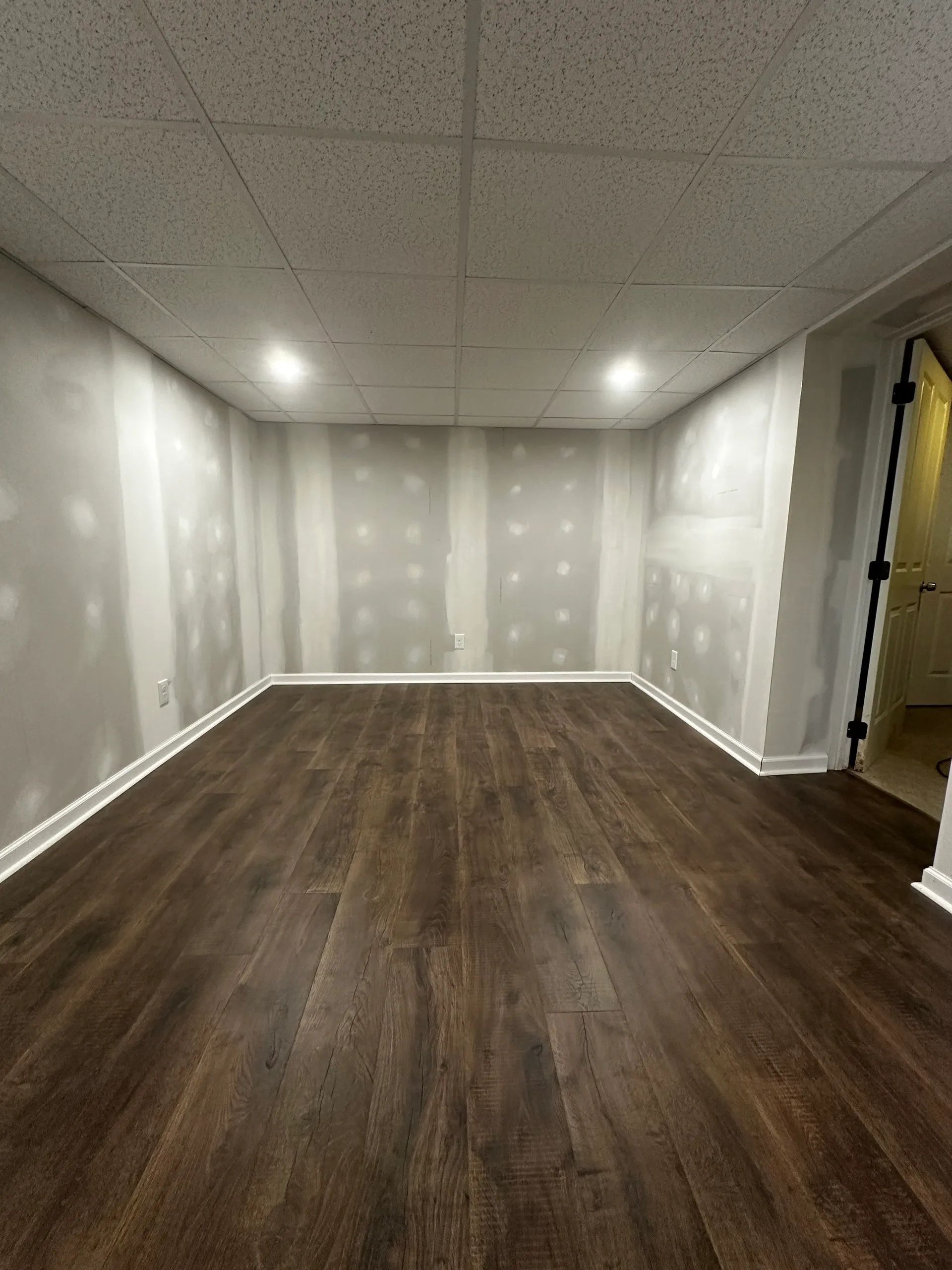 Empty room with wood-look flooring, unfinished drywall, and recessed ceiling lights