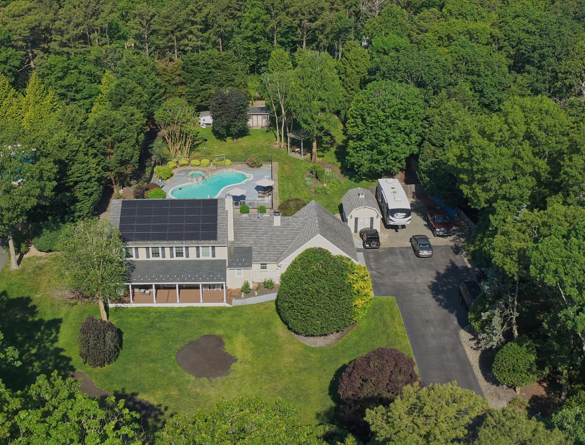 Blue single-story house with white trim and a concrete driveway in a wooded yard