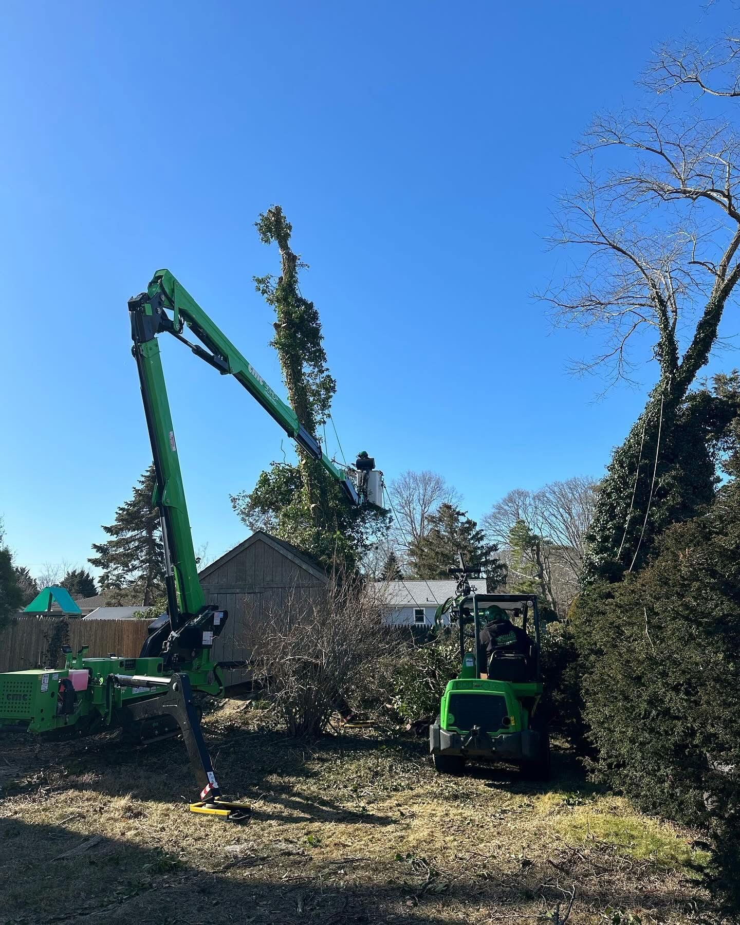 Two green construction lifts working near a house on a sunny day