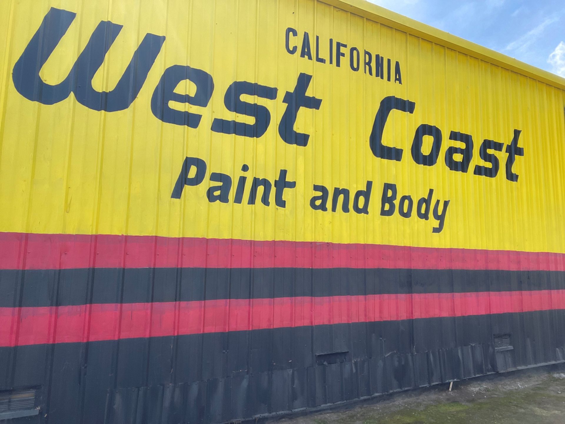 A yellow building with the words west coast paint and body painted on it