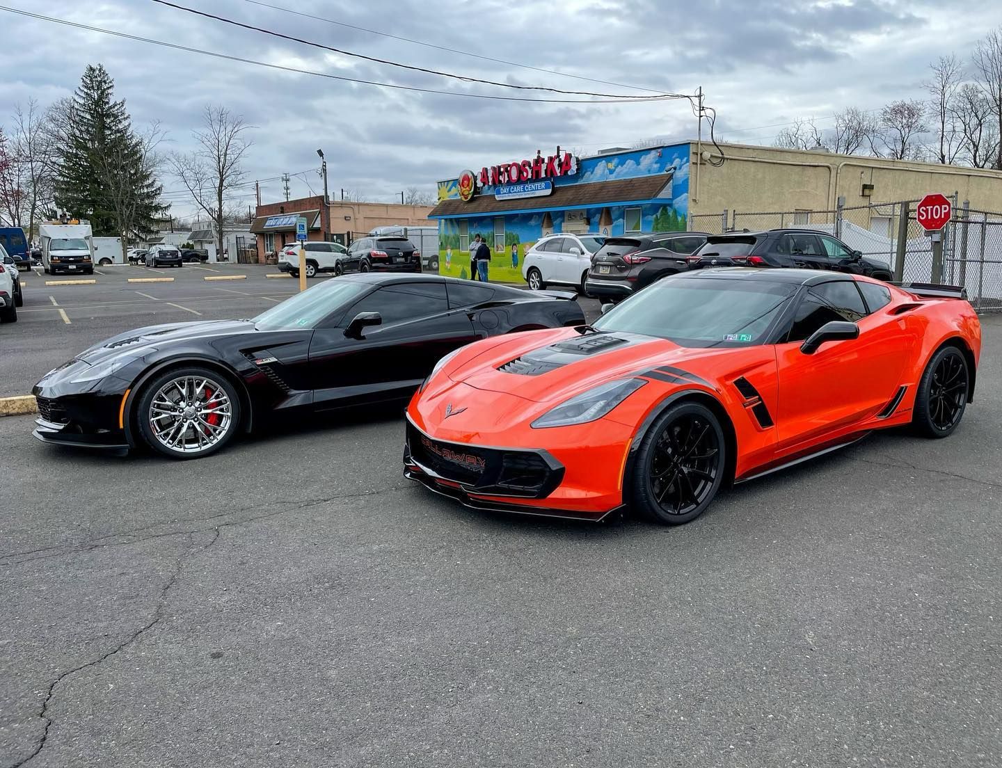Two Chevrolet Corvette sports cars, black and orange, parked in a lot.