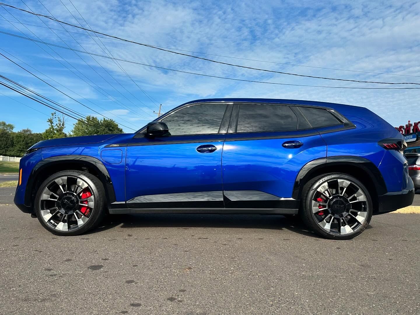 Blue SUV with tinted windows and black and chrome wheels parked on a street.