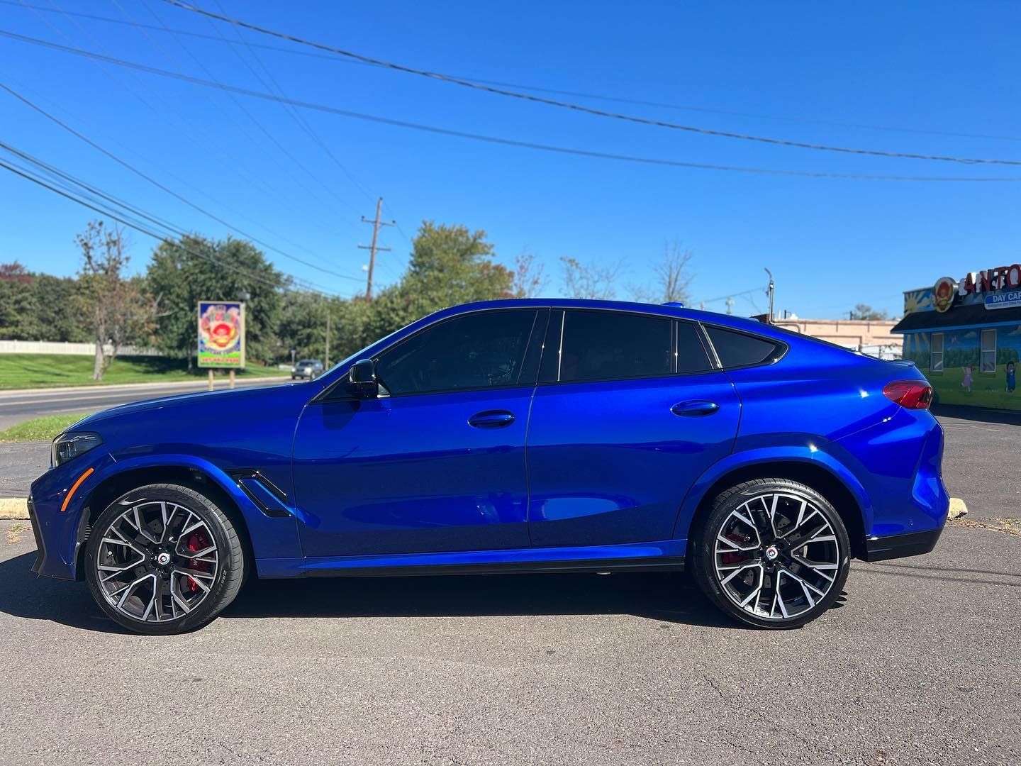 Blue BMW X6 SUV with tinted windows, parked on asphalt on a sunny day.