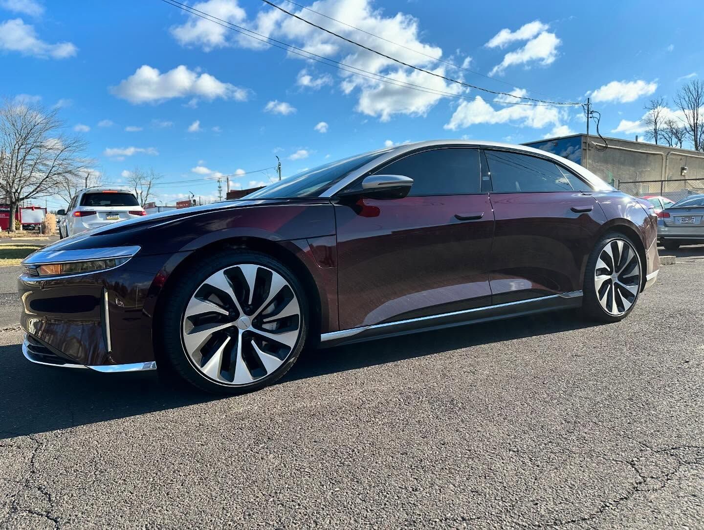 Maroon Lucid Air electric car parked outside on a sunny day.
