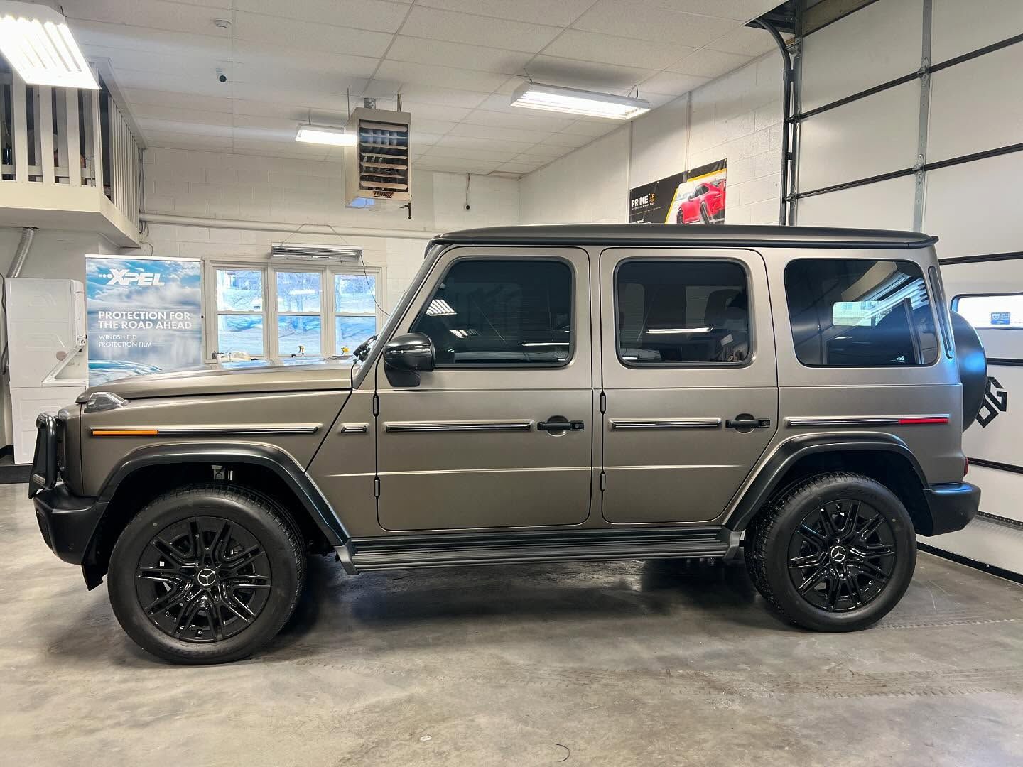 Gray Mercedes-Benz G-Class SUV with black wheels parked inside a garage.