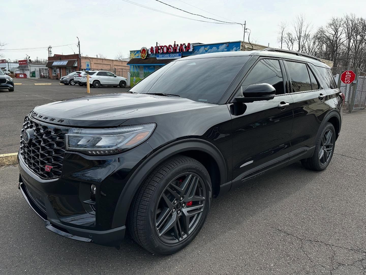 Black Ford Explorer SUV parked on pavement. Dark tinted windows, red brake calipers.
