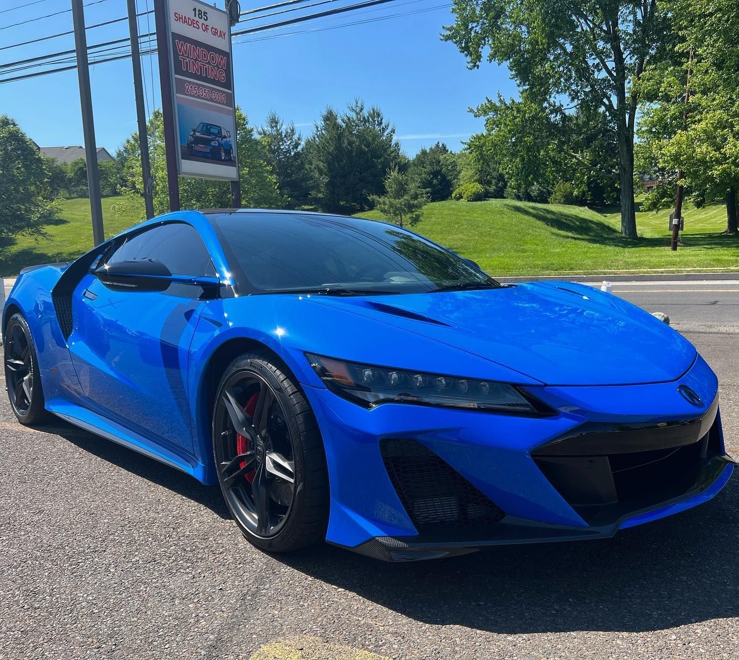 Blue Acura NSX sports car parked outside a shop on a sunny day.