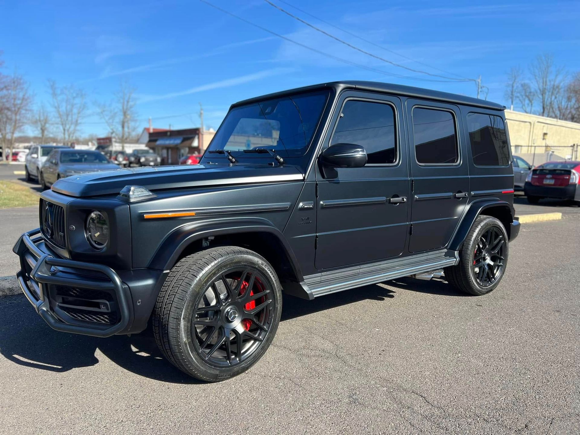 Dark gray Mercedes-Benz G-Class SUV with black wheels and red brake calipers parked on pavement.