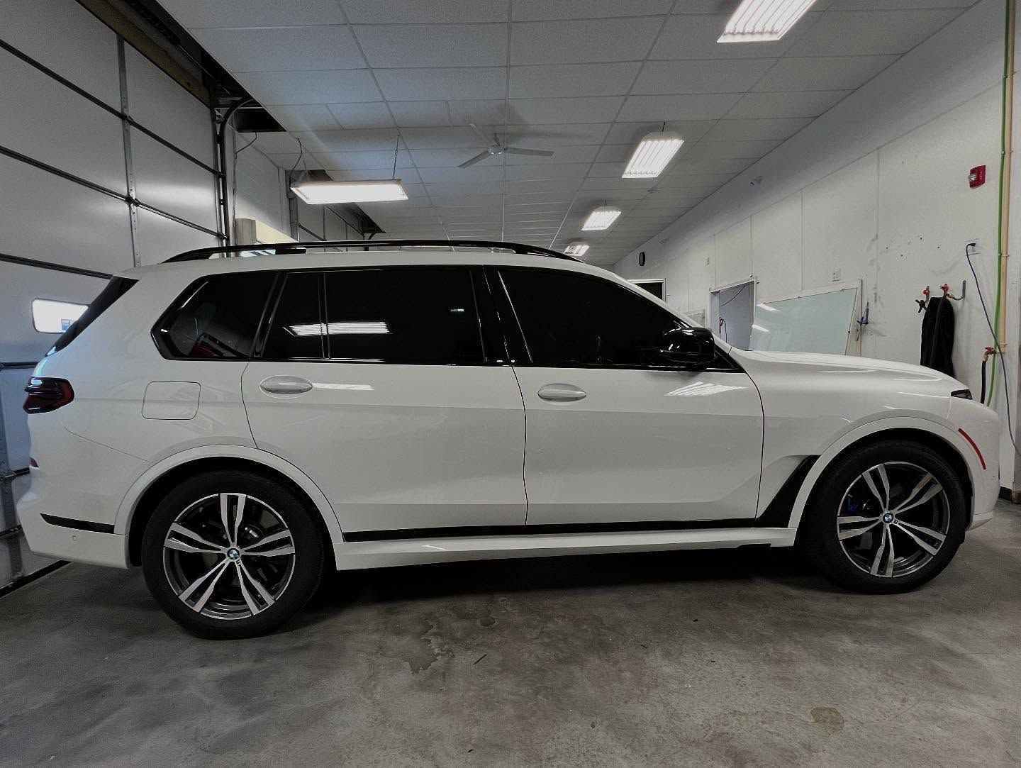 White BMW X7 SUV parked in a garage with tinted windows and black trim.