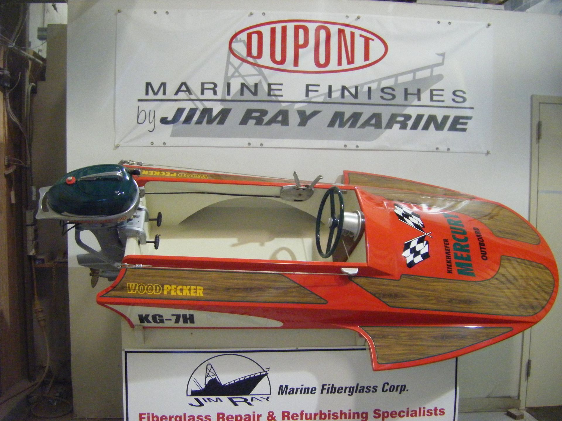 A boat is displayed in front of a sign that says qupont marine finishes