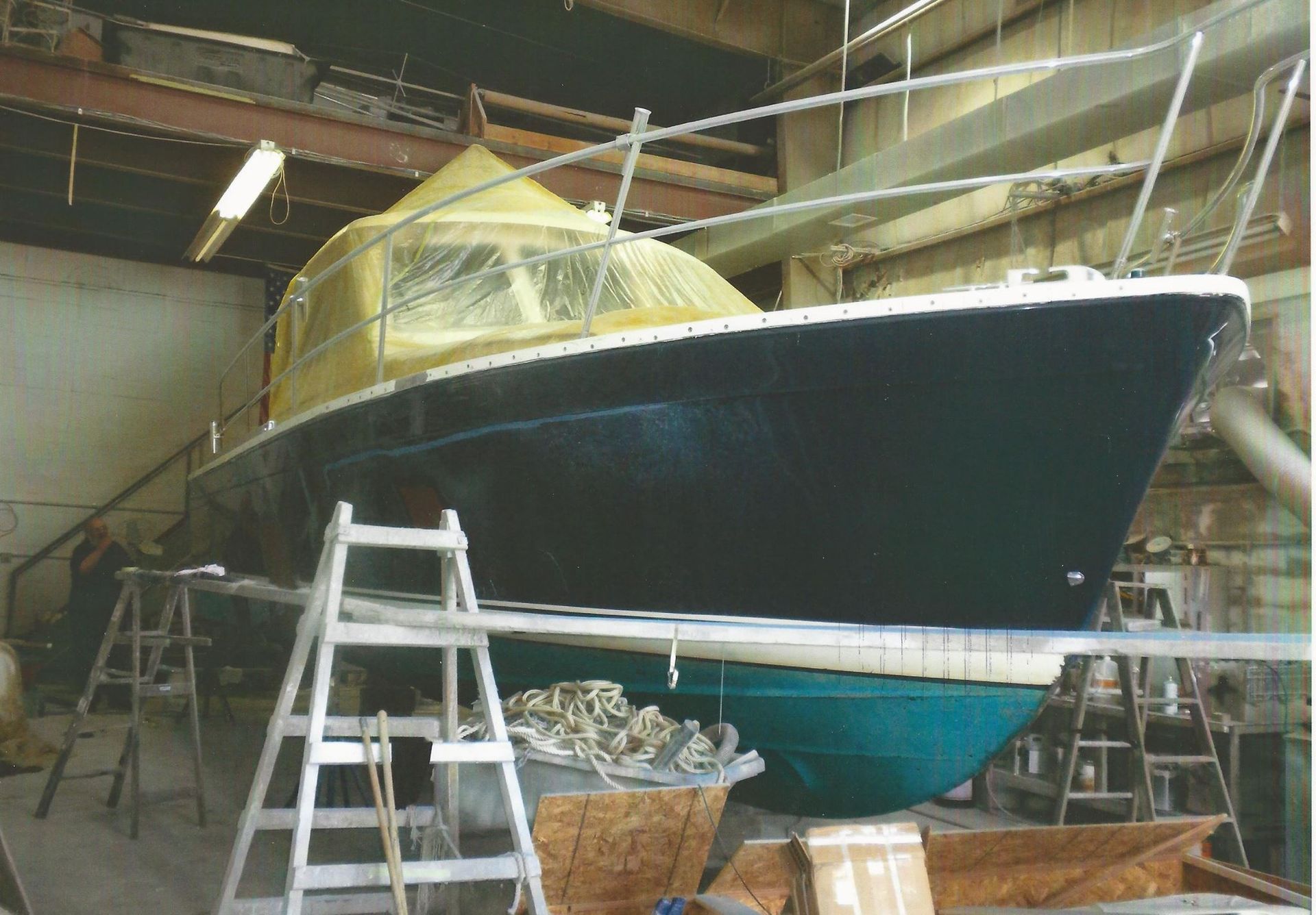 A boat is being painted in a garage with a ladder in the foreground