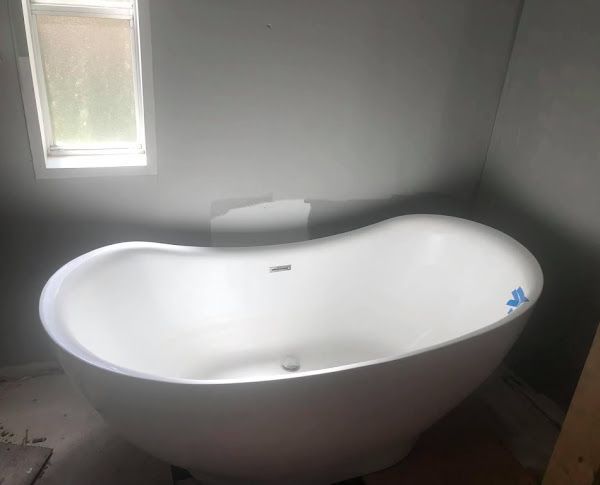 A white bathtub is sitting in a bathroom next to a window.