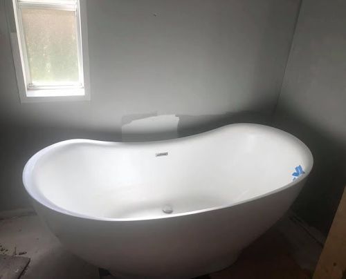 A white bathtub is sitting in a bathroom next to a window.