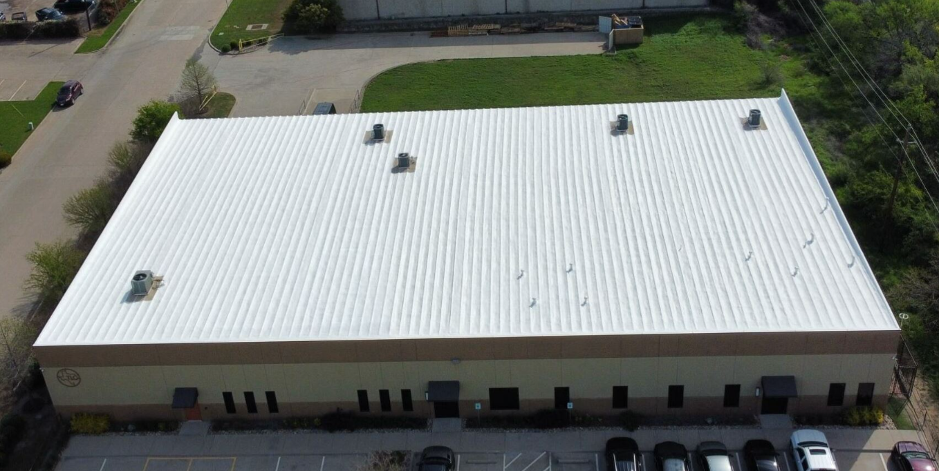 An aerial view of a large building with a white roof.