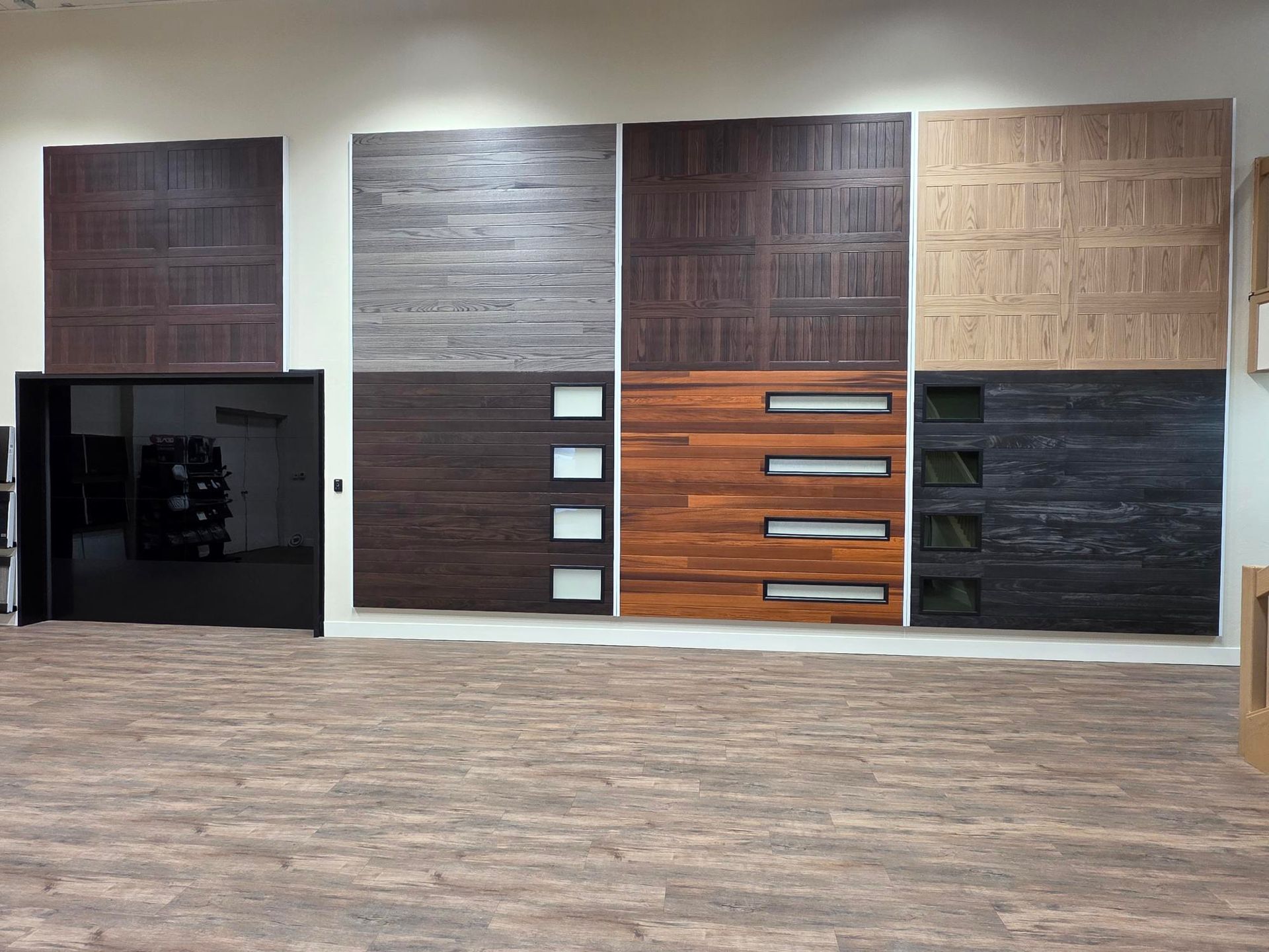 Garage door samples in various styles and colors displayed on a wall.