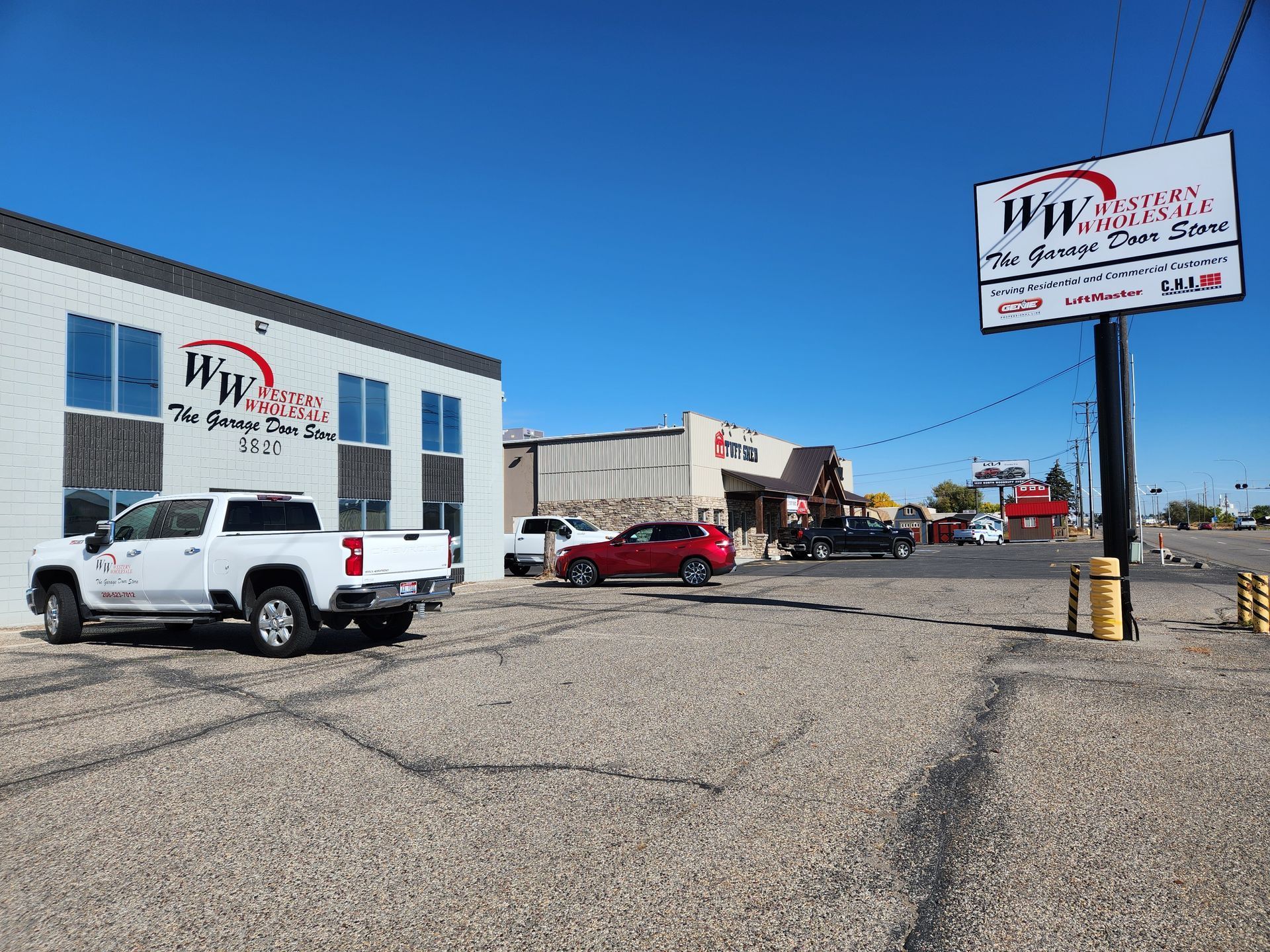 Exterior view of businesses with signage. White truck parked in front. Blue sky.