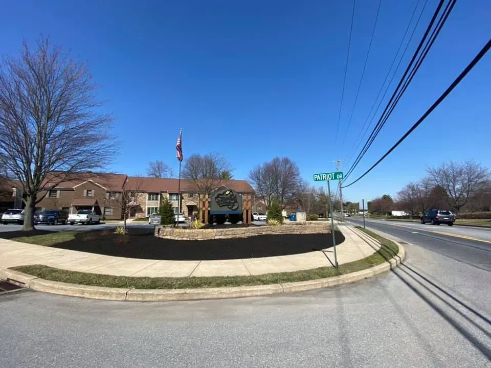 Street view of a brick building with a landscaped entrance, under a clear blue sky.