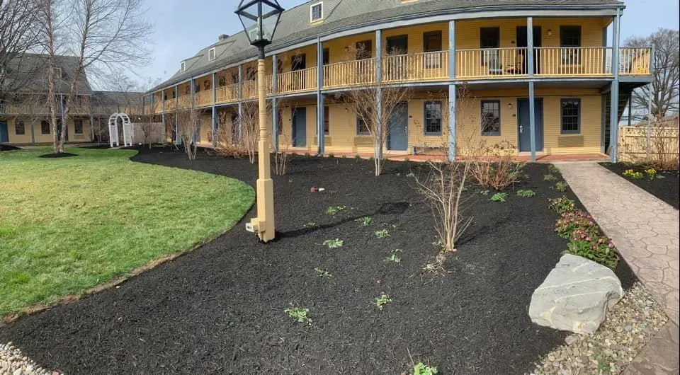 Exterior of a yellow two-story building with balconies, a lamp post, and a lawn.