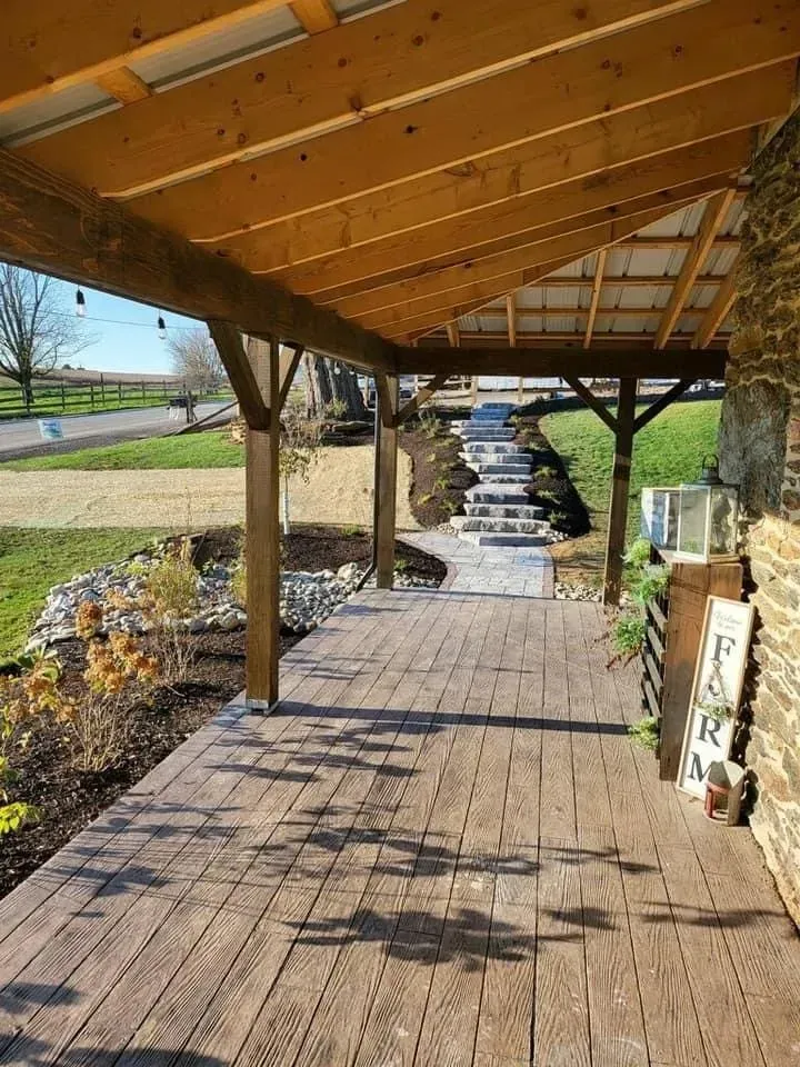 Covered wooden porch with stone wall, steps, and landscaping.