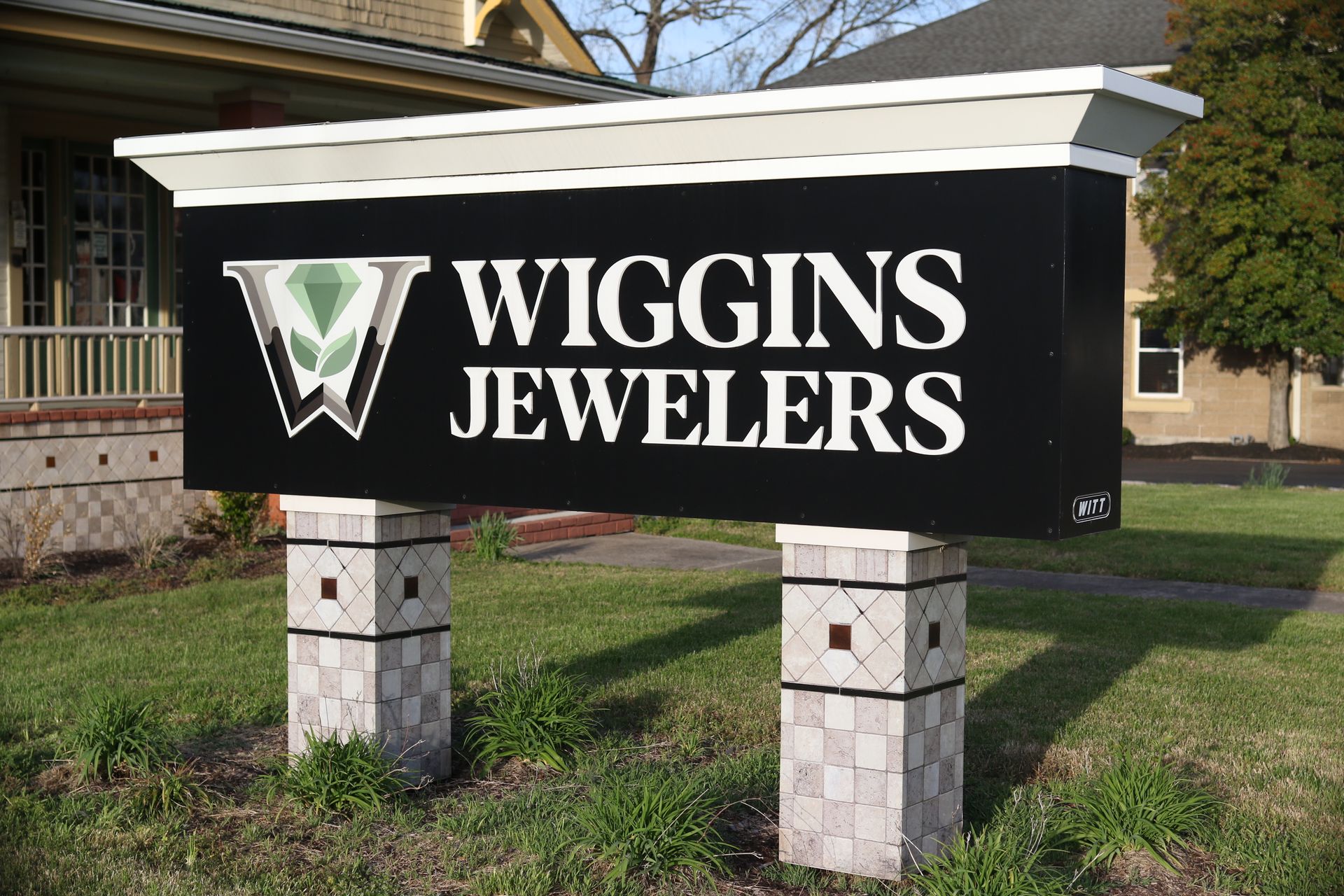 A sign for wiggins jewelers is in front of a house