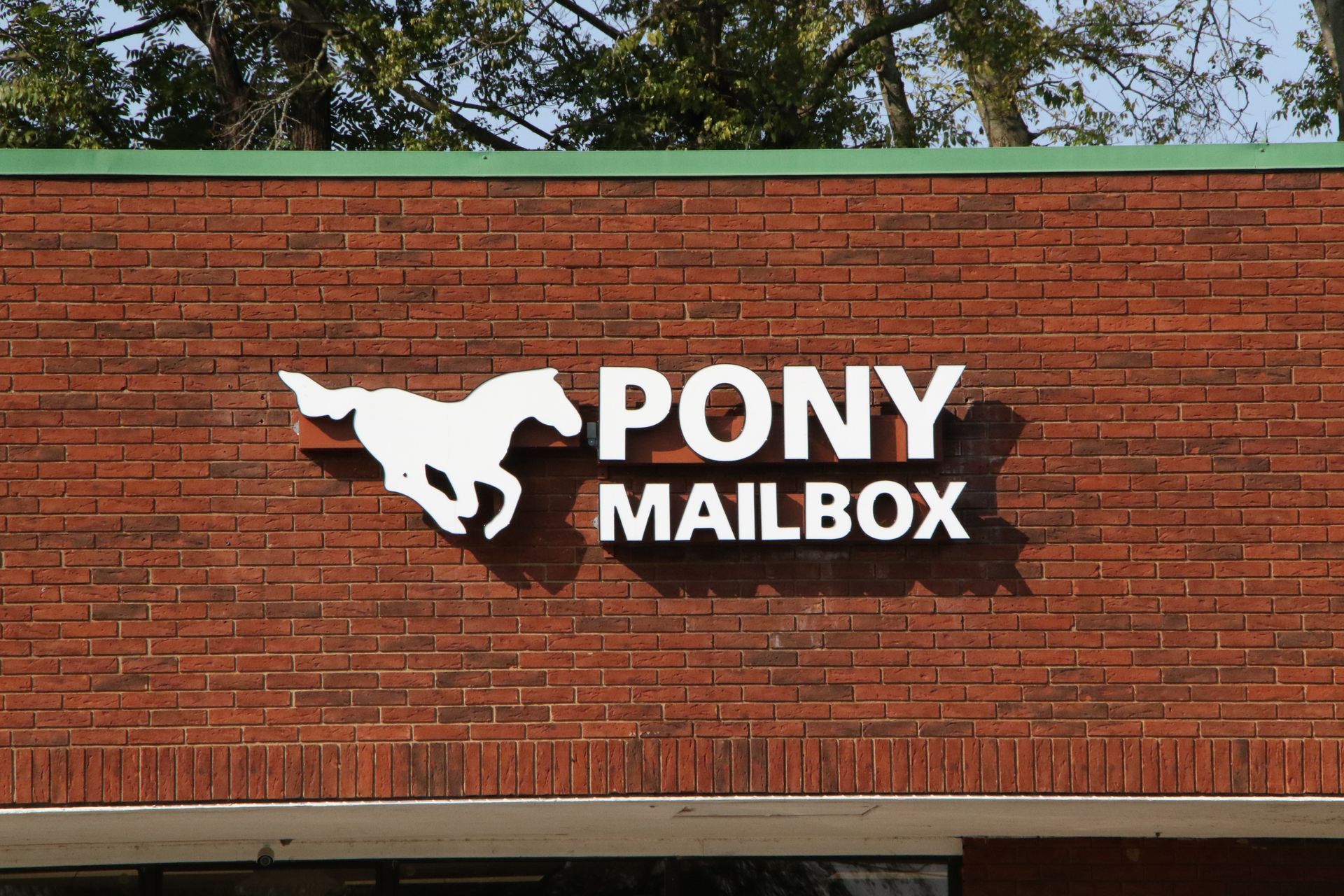 A pony mailbox sign on a brick building