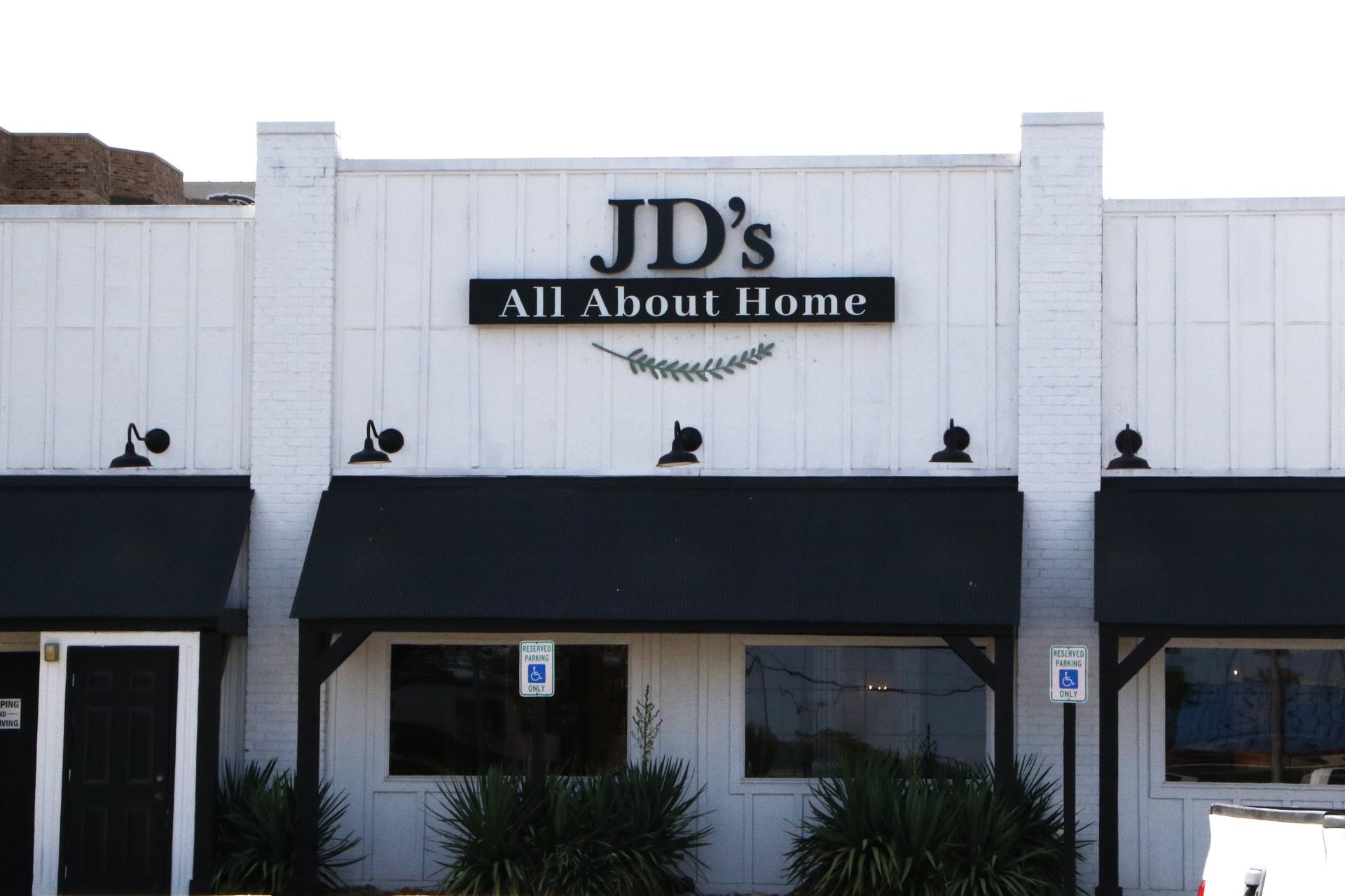 A white building with a black awning that says jd 's all about home