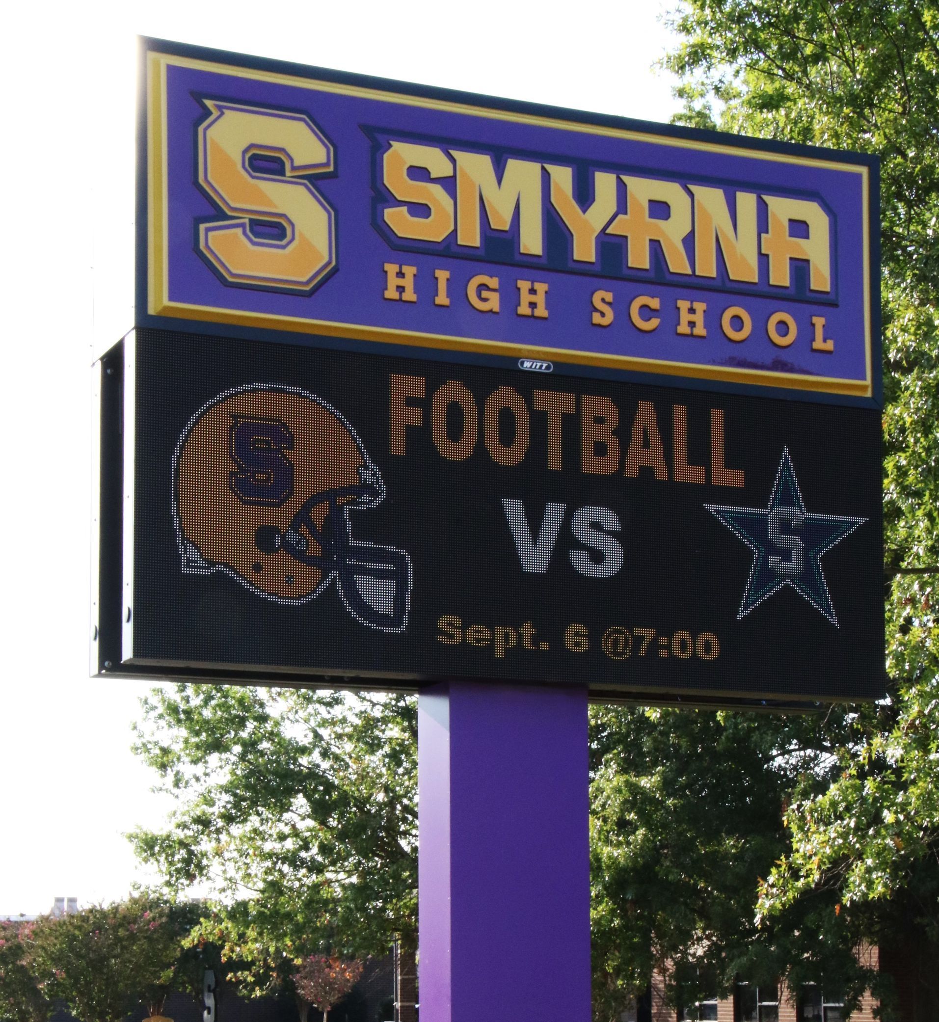 A sign for smyrna high school shows a football game