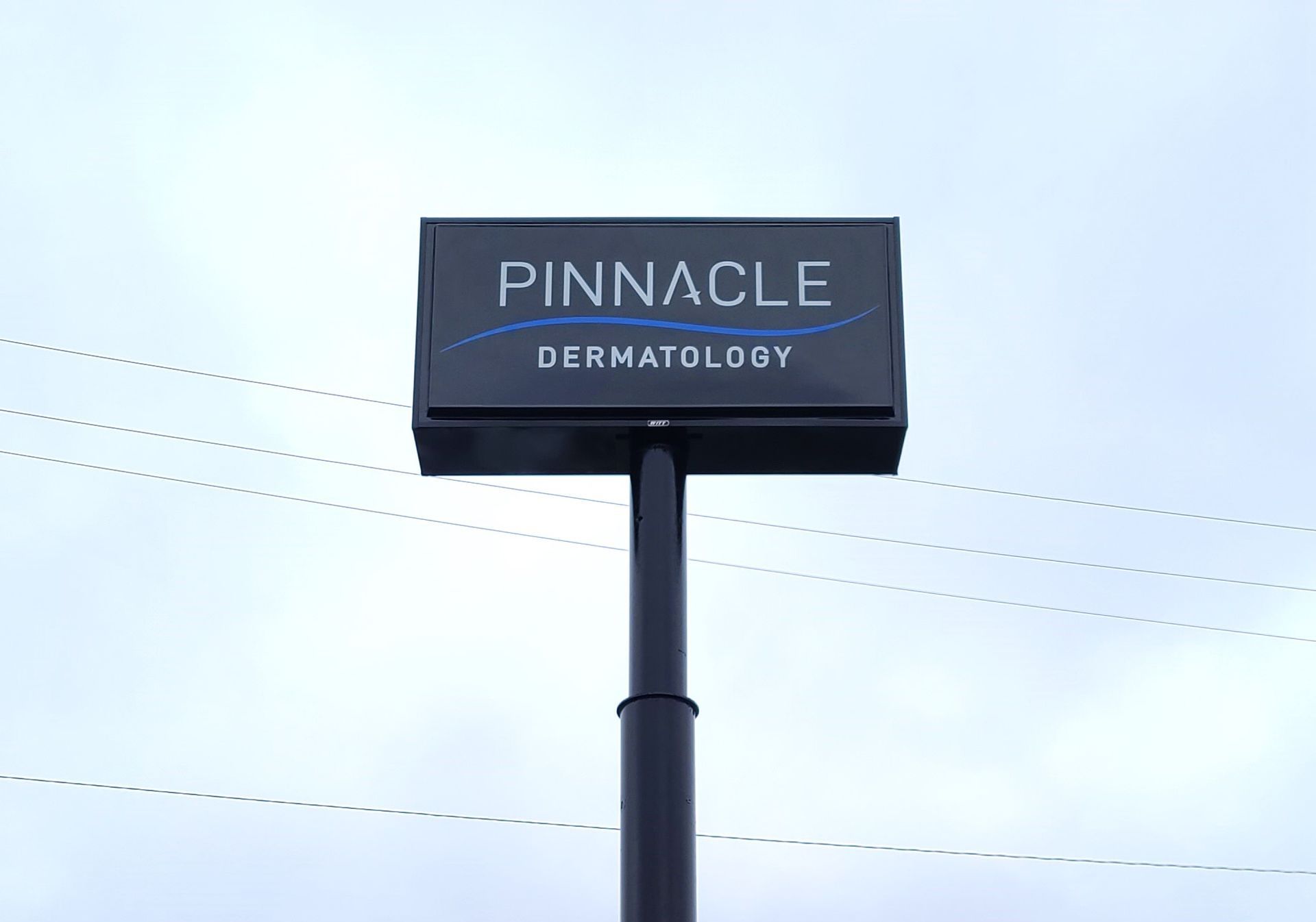 A tall black sign that says pinnacle on it is in a parking lot.