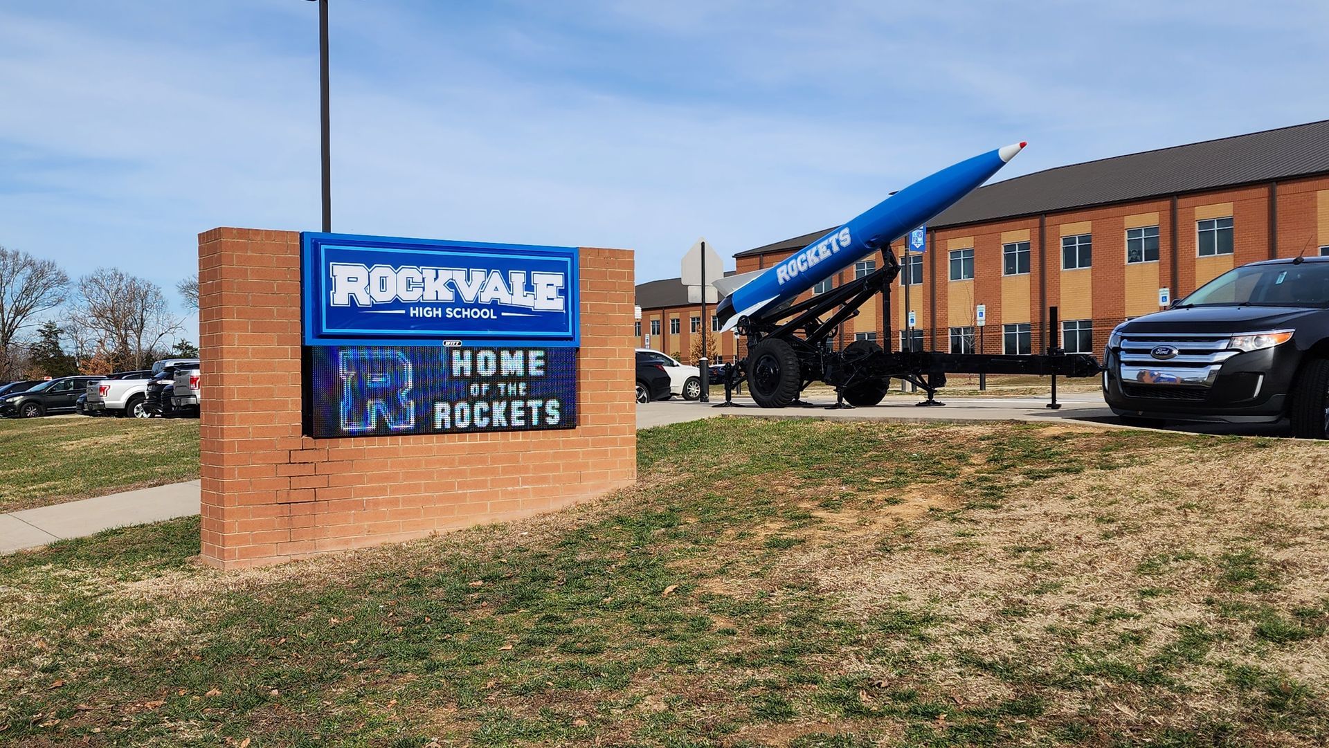 A car is parked in front of a sign that says rockvale home of the rockets.