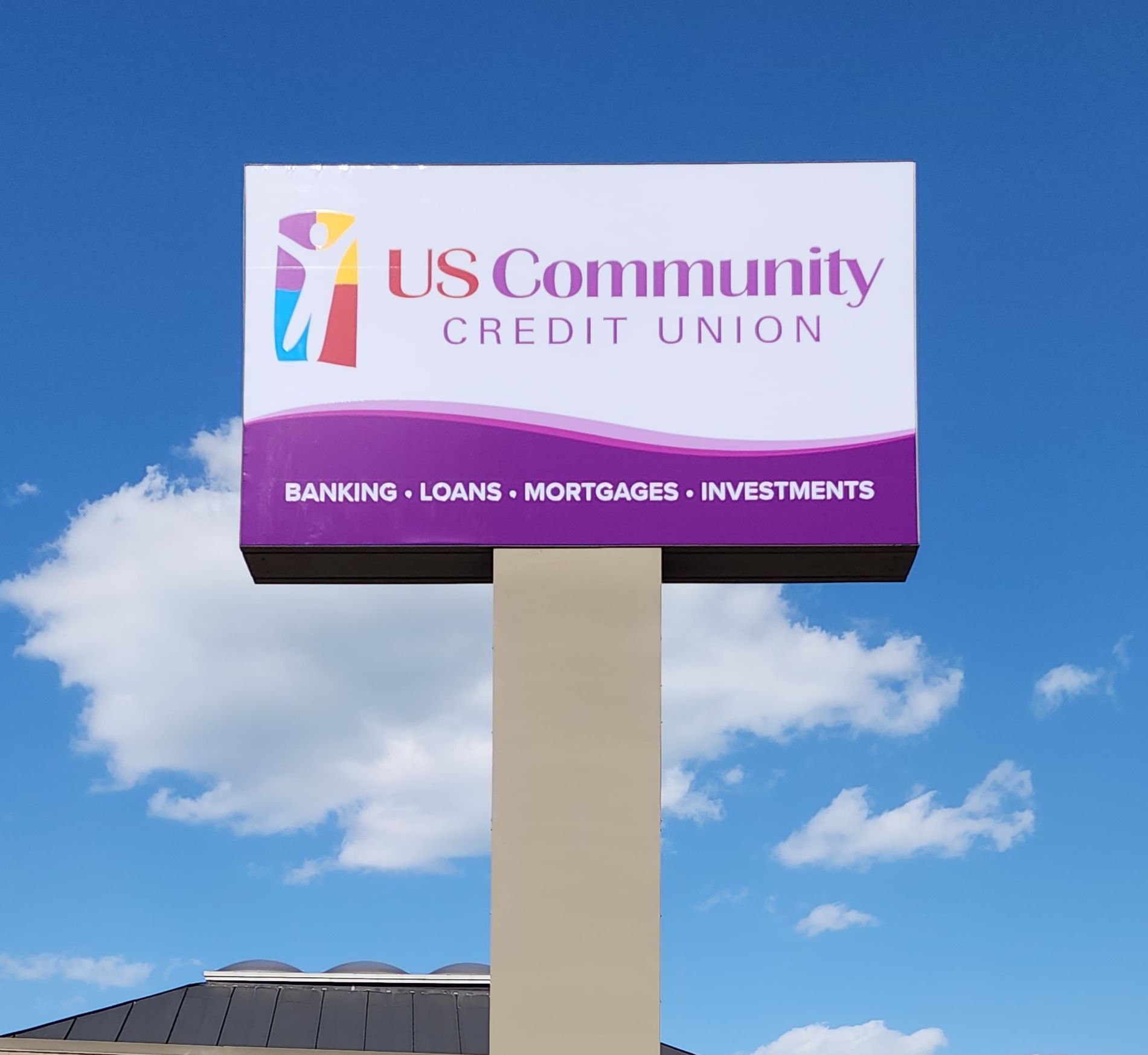 A us community credit union sign is in front of a building.