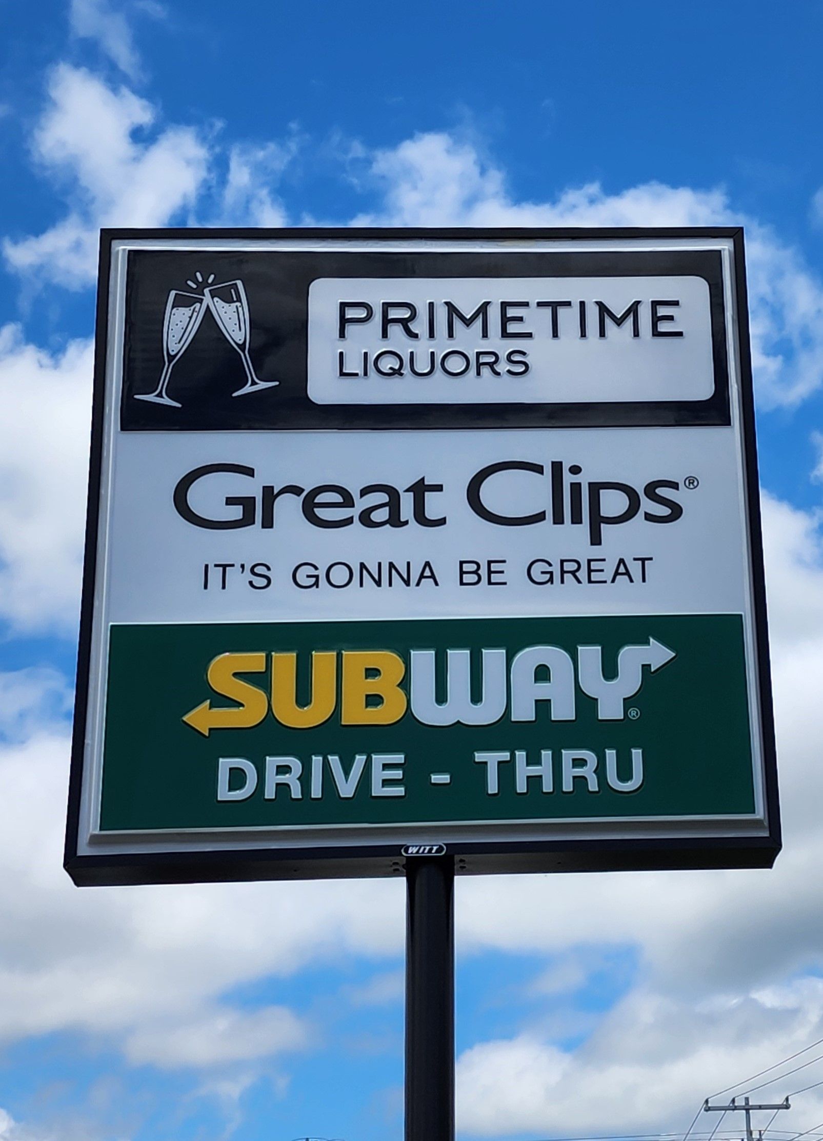 A sign for primetime liquors great clips and subway drive thru