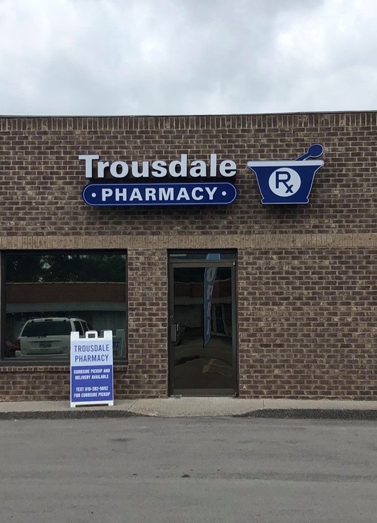 The front of a brick building with a sign that says trousdale pharmacy.