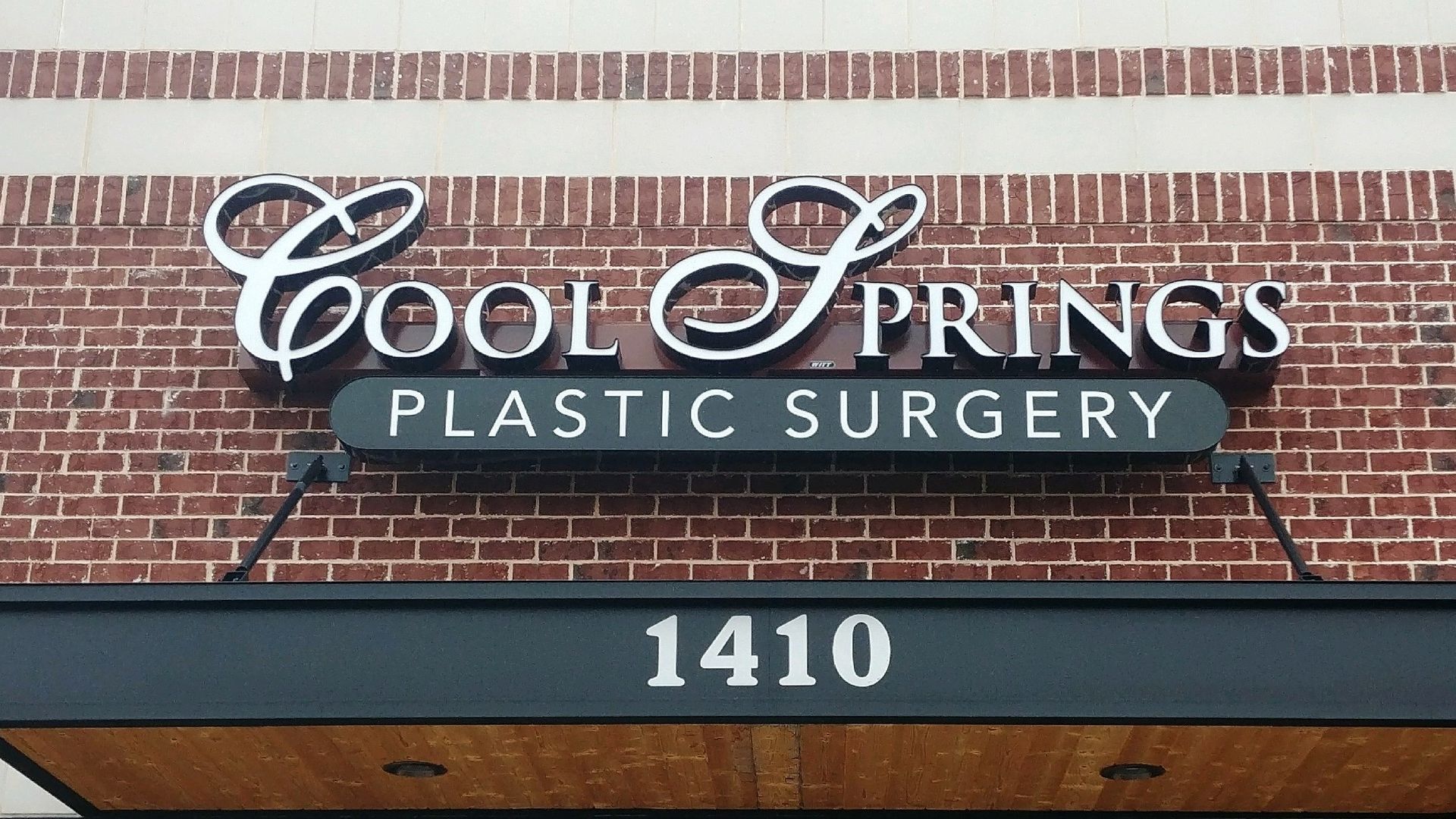 A cool springs plastic surgery sign on a brick building