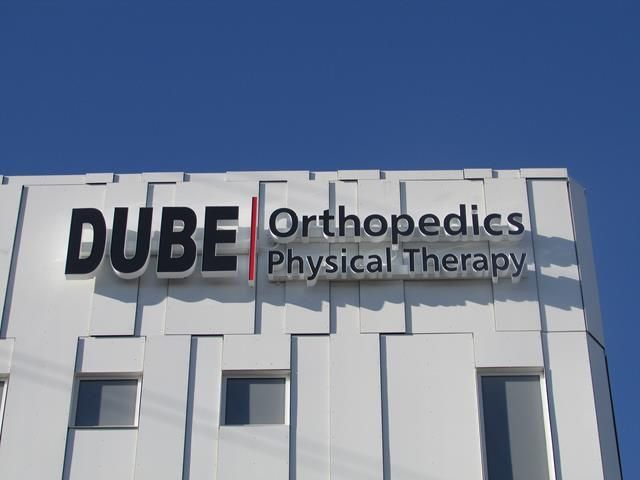 A white building with a sign that says dube orthopedics physical therapy