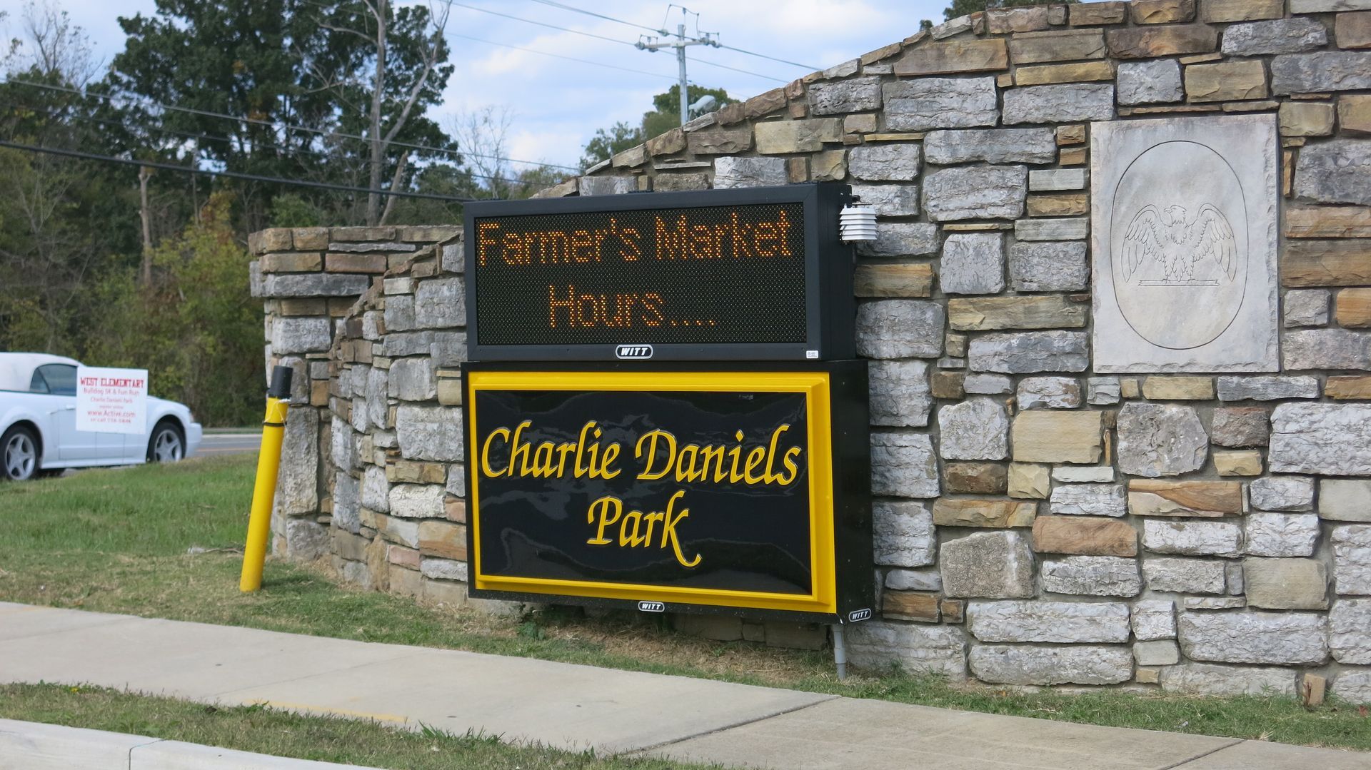 A sign for charlie daniels park is on a stone wall