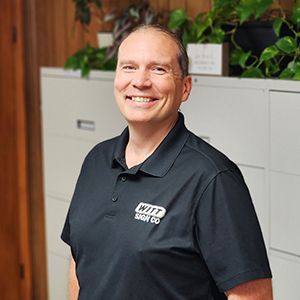 A man in a black shirt is smiling for the camera.