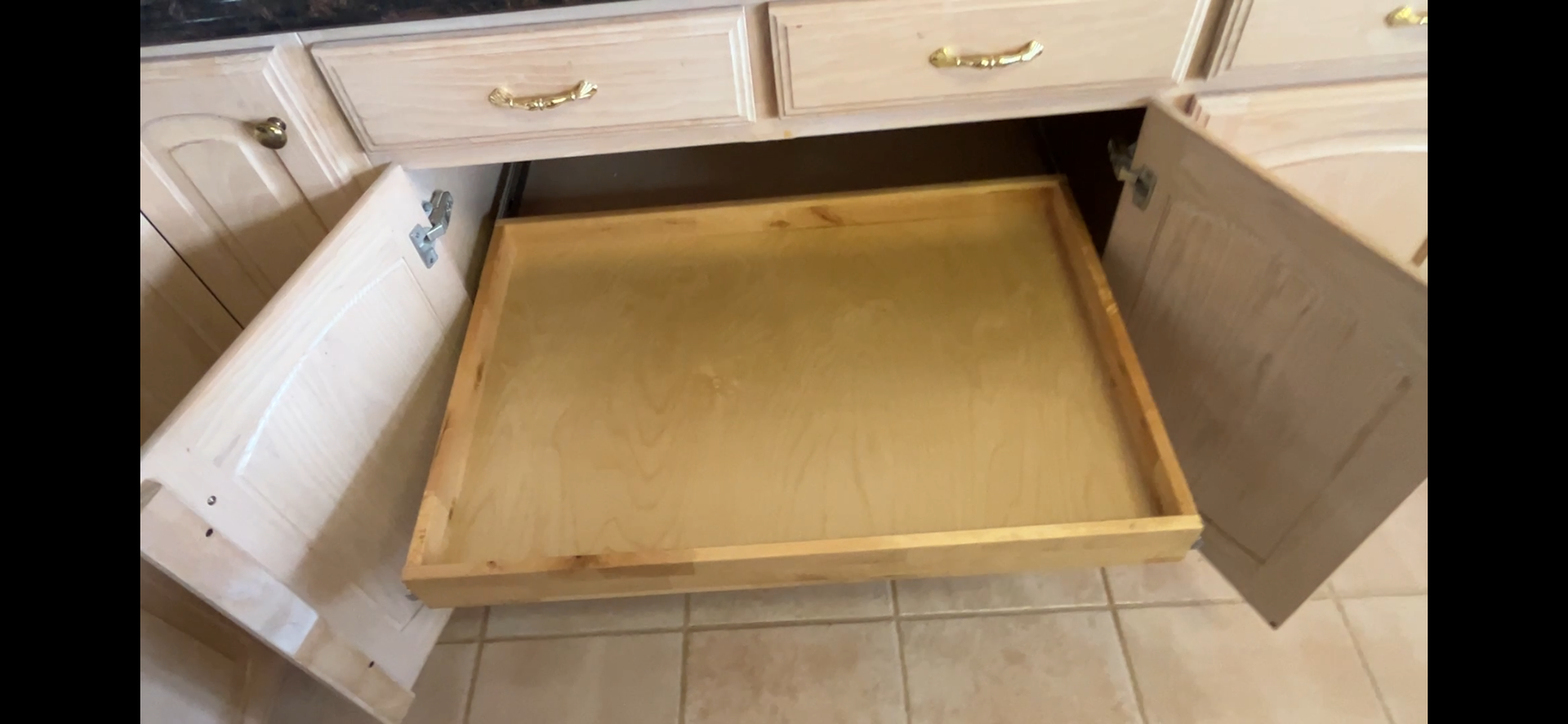 Custom pullout shelf extended from a kitchen cabinet with the center stile removed for wider access.