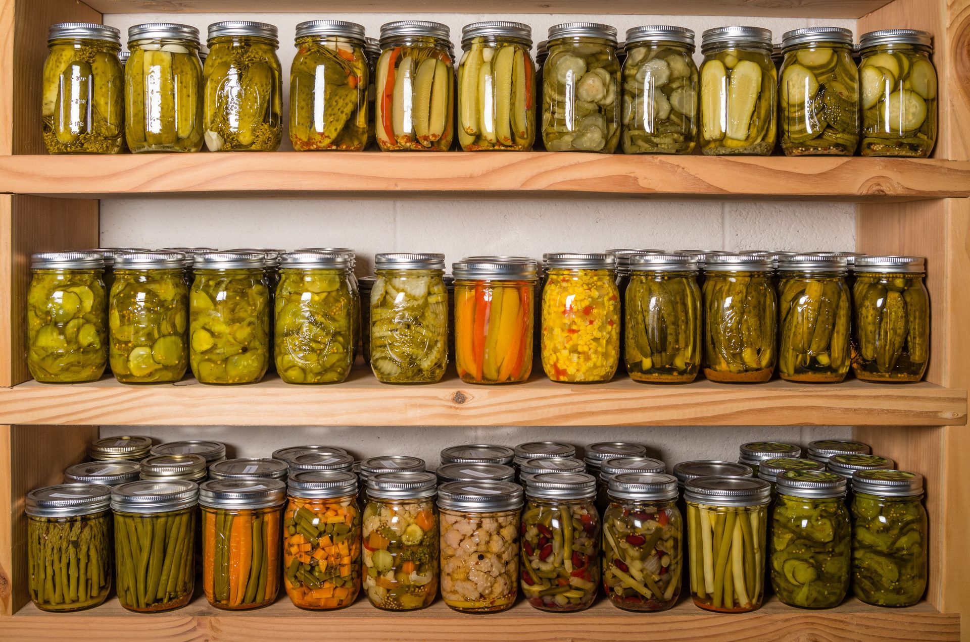 Shelves filled with various jars of preserved vegetables, pickles, and preserves.